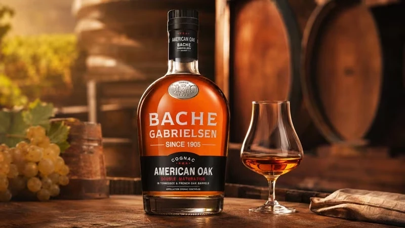 Bache Gabrielsen American Oak Cognac mit Cognacglas, Trauben und Eichenfässern