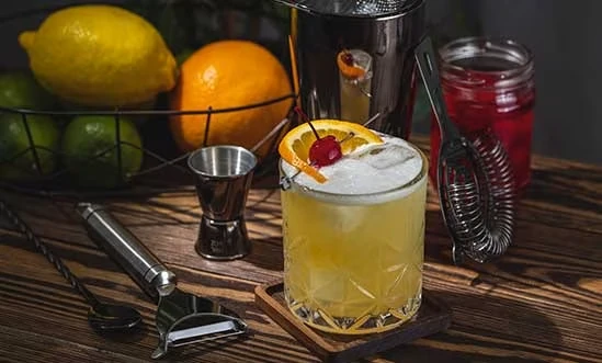 Bourbon Whiskey Cocktail Whiskey Sour mit Orange und Kirsche und Mixzubehör