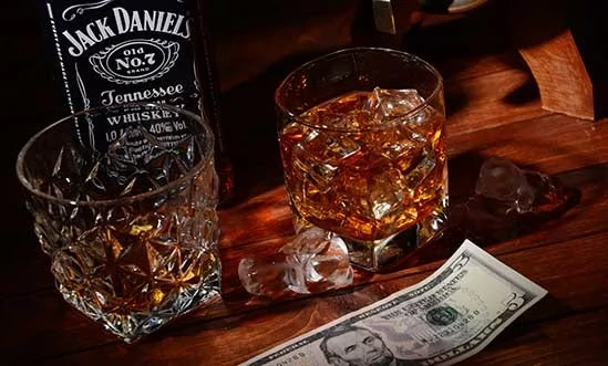 Amerikanischer Whiskey Bestseller Amerikanischer Whiskey im Glas, eine Jck Daniel's Flasche und US-Dollarnote